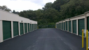 Drive aisle between two rows of green roll-up storage unit doors at Mills River Storage Center
